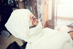 Mature male with beard receiving professional grooming, reclining in barbershop, a Person Photo by Antonio Gravante Market