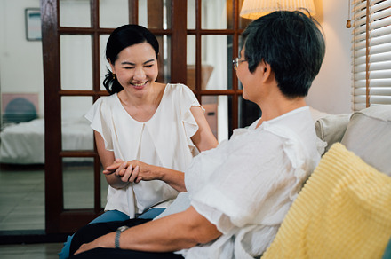 Asian daughter holding hand of senior mother