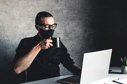 A masked man works at a computer.