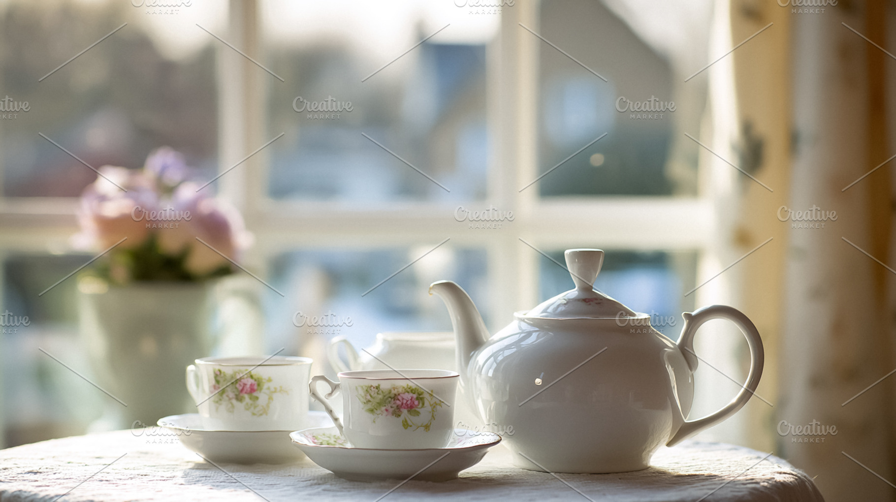 Teapot, tea cups, and saucers arranged on a table in front of a, a Photo by Studio ANNA