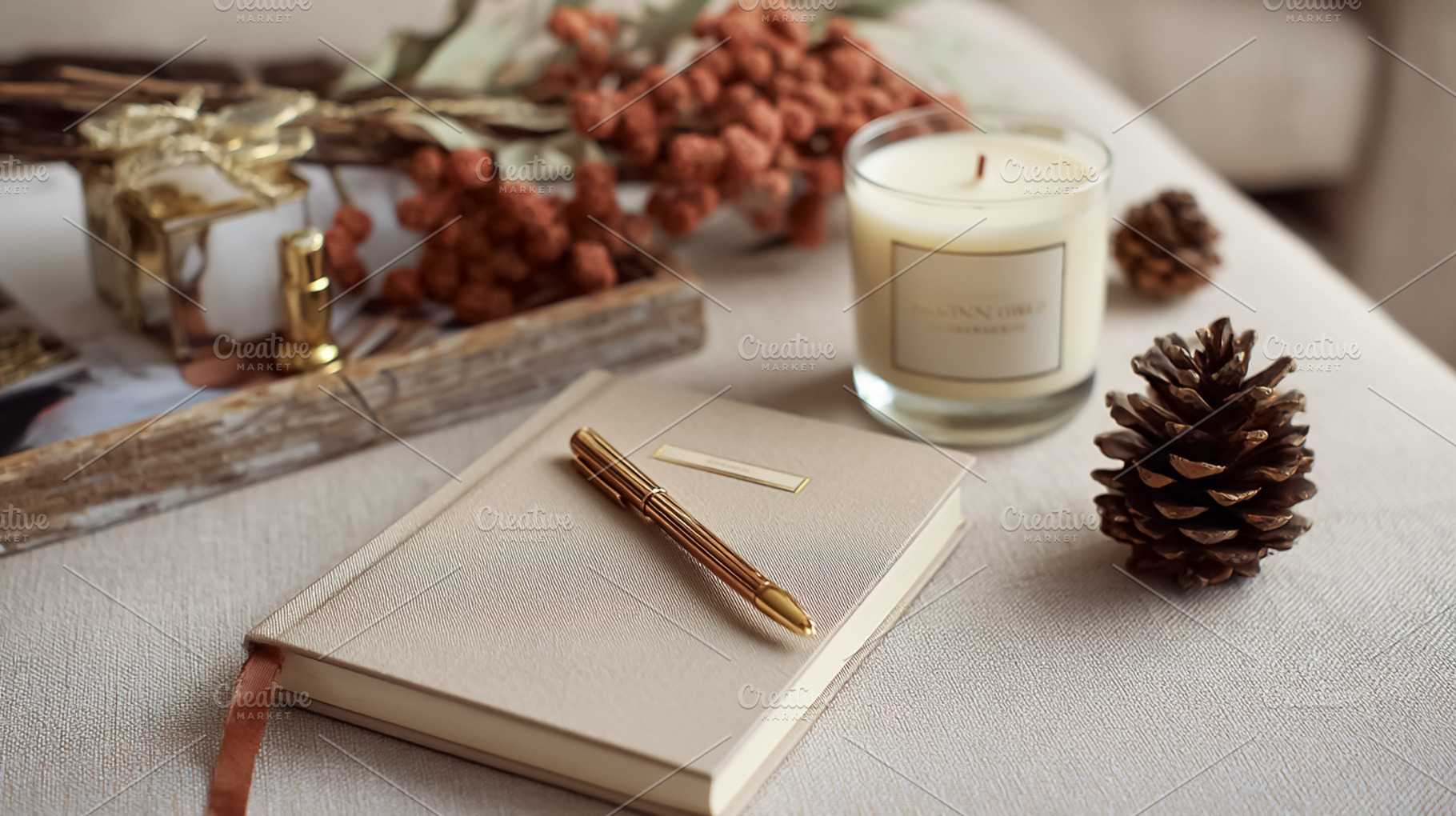 Journal with pen, burning candle, and pinecones creating a hygge, a Photo by Studio ANNA