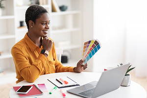 Creative young black woman designer working on laptop, a Photo by Prostock-Studio