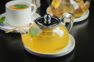 Fruit tea with mango and mint in a glass teapot on the table, a Food & Drink Photo by Budarinphoto