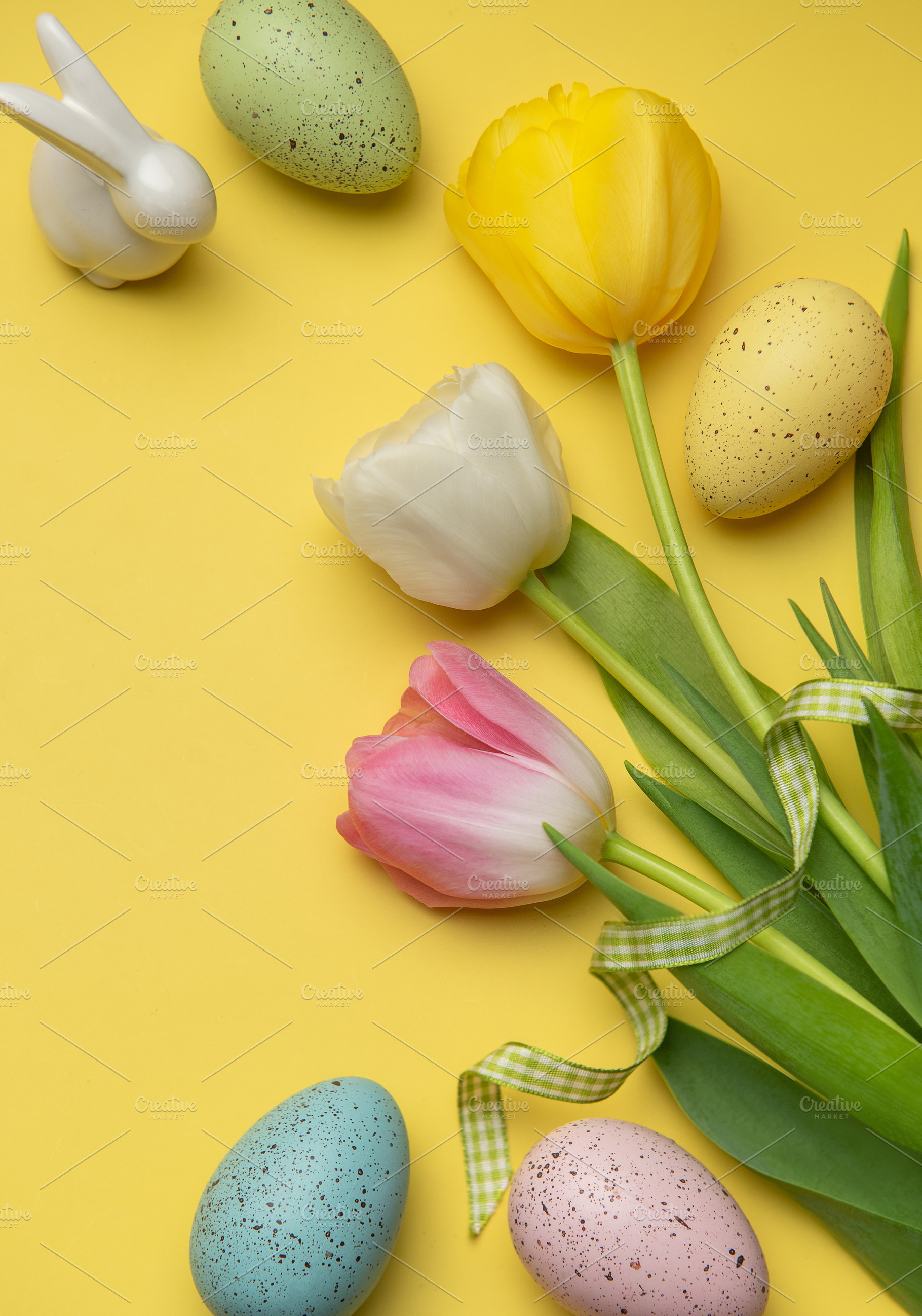 Easter eggs and tulips forming a frame on a yellow background, a Holiday Photo by Olena Rudo