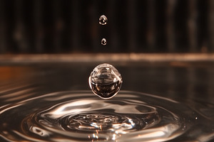 A close-up shot of a water droplet falling into a pool of water, creating rippl, a Photo by Textures & Backgrounds