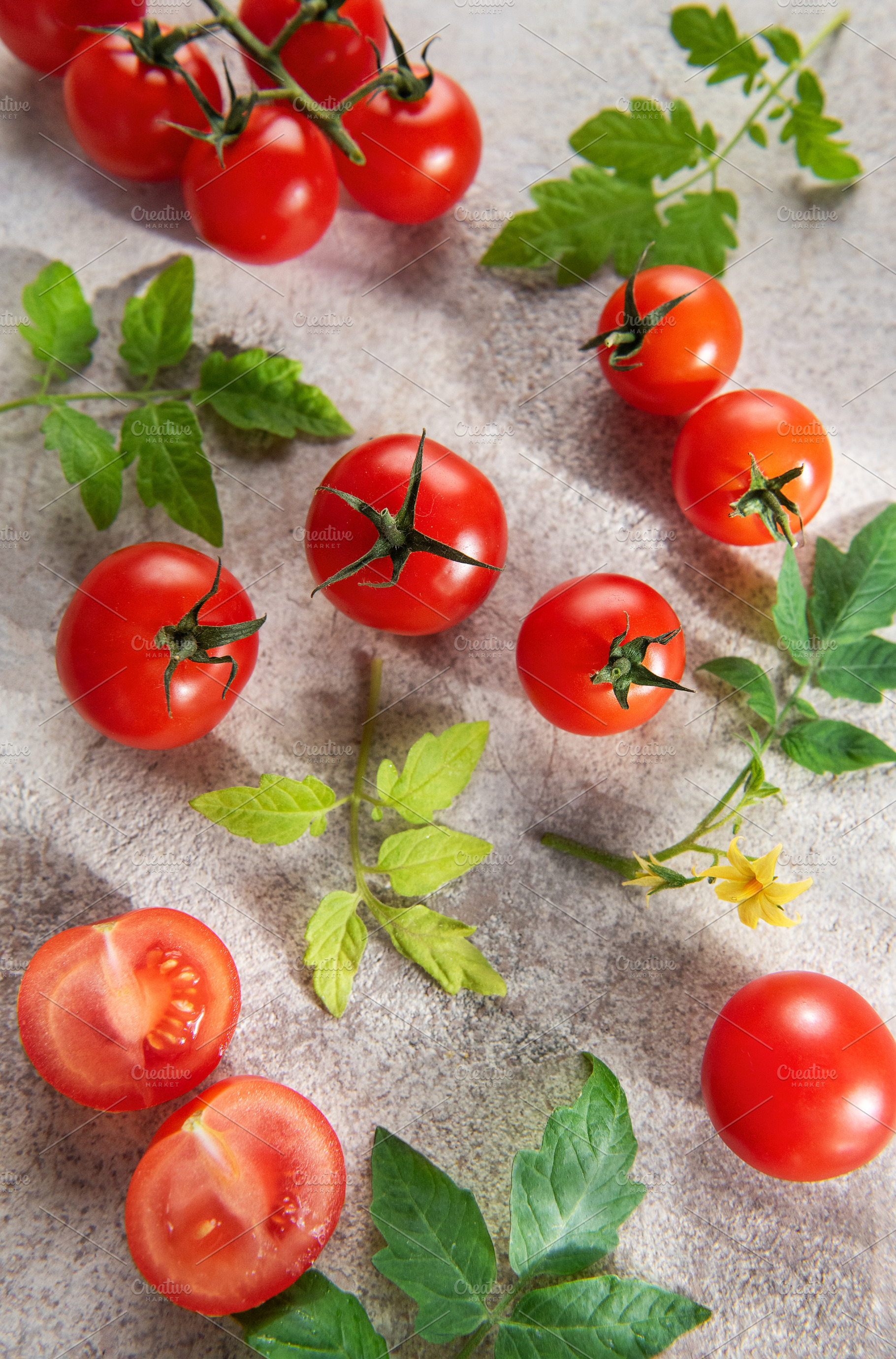 Fresh cherry tomatoes and leaves on light background, a Food & Drink Photo by Olena Rudo