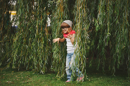 Little girl hiding in the willow foliage stock photo containing playing and