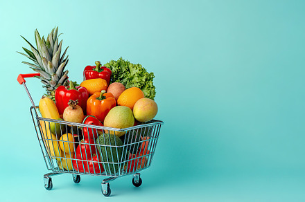 Shopping basket full of different grocery products on blue background, a Food & Drink Photo by AlyaAnd