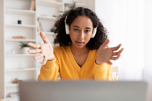 Young African American woman in headset having online meeting on laptop compute, a Photo by Prostock-Studio