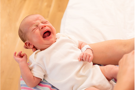Mom holds her screaming baby in her, a Health & Medical Photo by oksix
