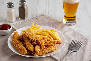Homemade Chicken Strips with Fries on a Plate, side view., a Food & Drink Photo by LiudmylaChuhunova
