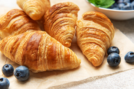 Delicious golden brown croissants with fresh blueberries resting