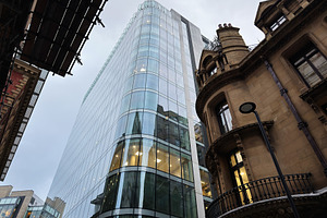Modern glass skyscraper towers over historic brick building in Manchester city, a Photo by AS photostudio
