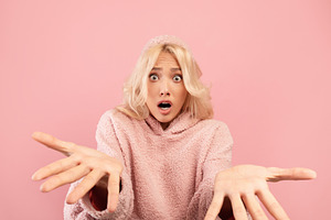 Omg. Portrait of shocked young woman looking and spreading hands at camera, exp, a Photo by Prostock-Studio