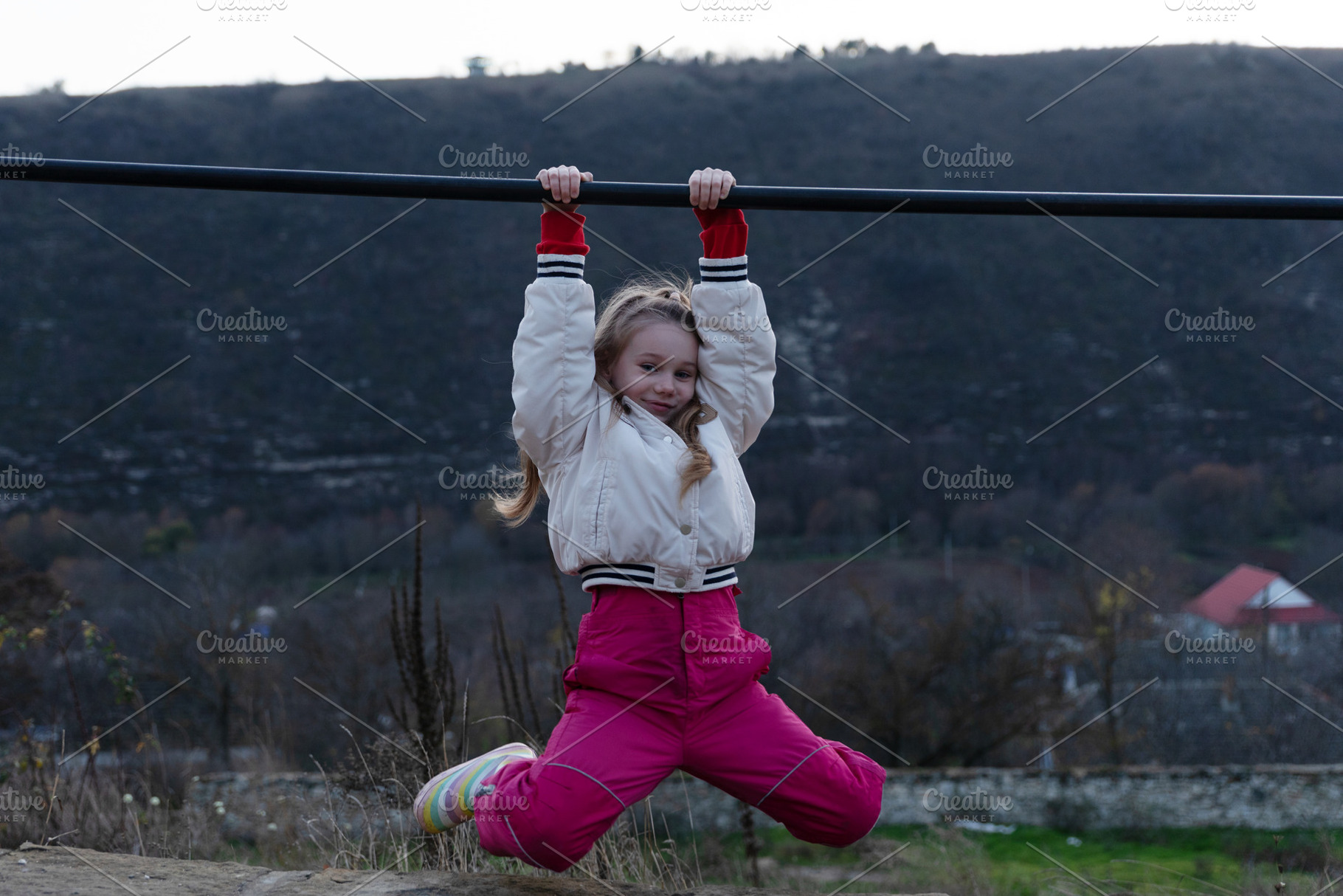 Smiling young girl in winter clothes hanging from a horizontal b, a Person Photo by Ales Munt