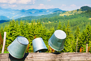 Empty buckets on fence with mountain landscape, a Nature Photo by Vapi