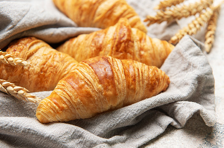 Freshly baked croissants resting on a linen cloth with wheat sta