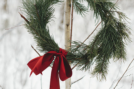 Stylish Christmas wreath with pine branches and red bow hanging, a Holiday Photo by Sonjachni