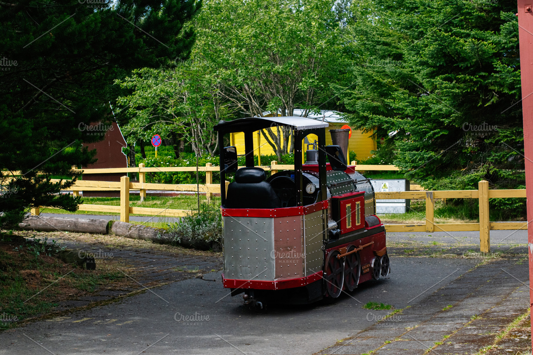 Colorful small train model in Reykjavik Iceland surrounded by vibrant green tre, a Photo by AS photostudio