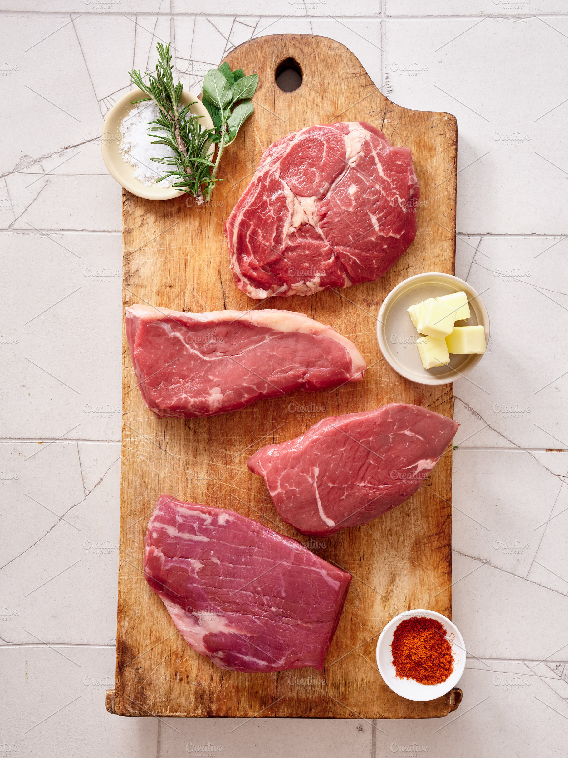 Raw rib-eye, roast beef, flank and rump steak prepared on a wooden cutting boar, a Food & Drink Photo by Asya Nurullina