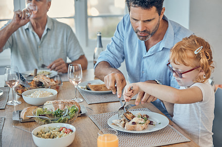 Restaurant, daughter and father with cutting, food or meat on table for learning, teaching and help. Dad, girl and lunch together with fork, knife and plate and helping kid with meal with family, a Photo by Peopleimages.com