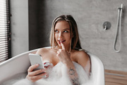 Mysterious caucasian woman using mobile phone while lying in foamy bath, textin, a Photo by Prostock-Studio (Thumbnail 1 of 3)
