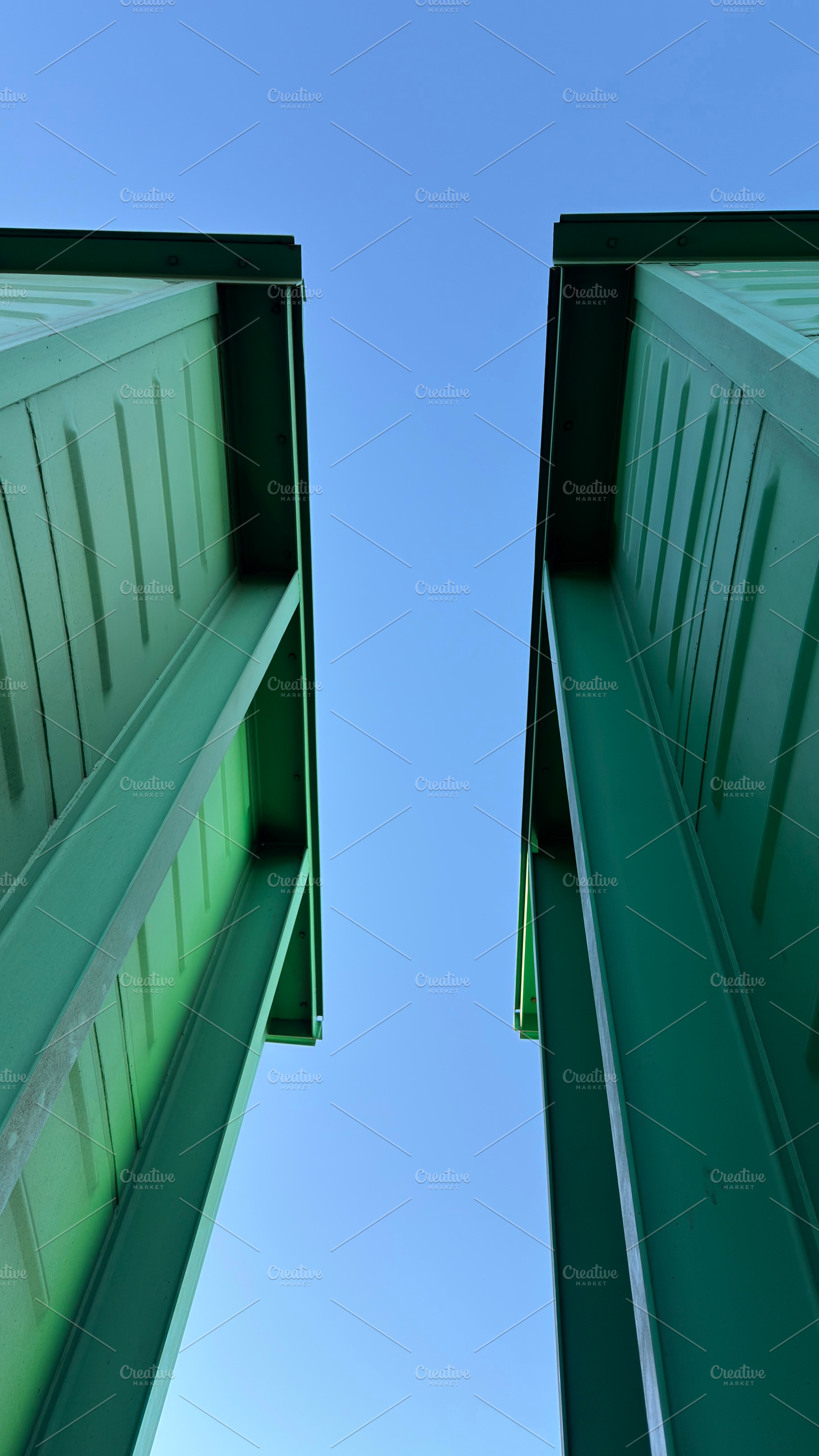 A low-angle view of two green containers against a clear blue sky, an Industrial Photo by Textures & Backgrounds