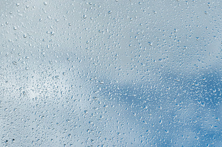 Raindrops on a window with a blue cloudy sky in the background., an Abstract Photo by Eugene_Photo