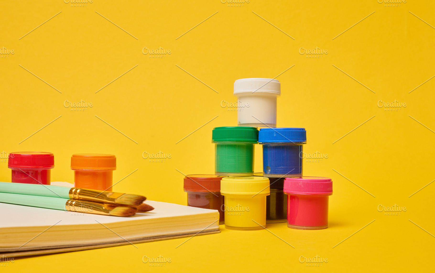 White spiral notebook, brushes and colorful paint cans symbolizi, a School & Education Photo by ndanko