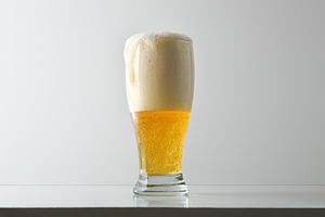 Glass of foamy beer on table and white isolated background, a Food & Drink Photo by Davizro's Market