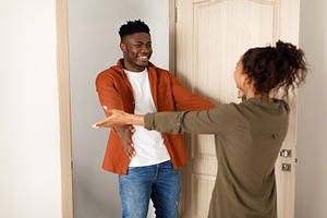 Cheerful Black Couple Stretching Hands For An Embrace At Home, a Photo by Prostock-Studio