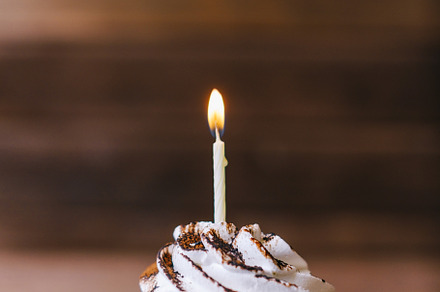 Cream cupcake with one candle. 