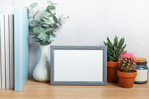 Blue picture frame standing on wooden desk with plants and books, a Business Photo by Olena Rudo