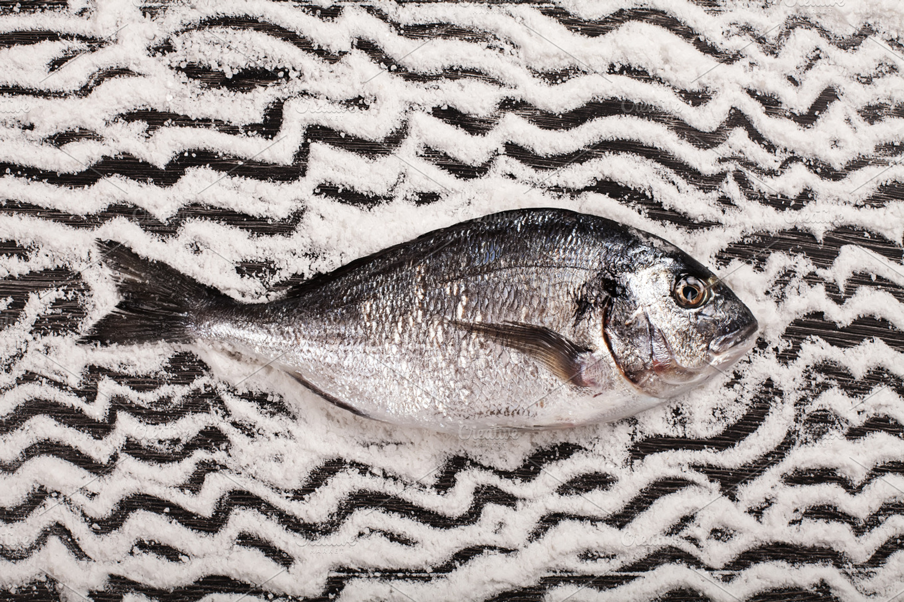 Fresh dorado fish on salt and dark wooden background featuring background