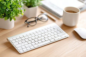 Wireless keyboard setup with plants and coffee in a distraction-free workspace, a Technology Photo by AlyaAnd