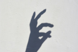 Shadow of a hand on a light wall showing the okay gesture., an Abstract Photo by ndanko