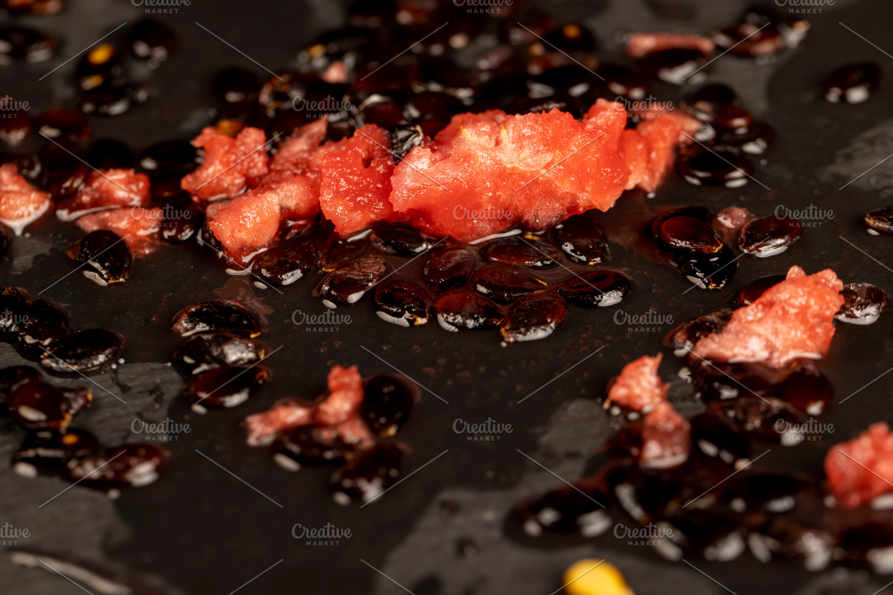 watermelon seeds and red pulp on black slate, a Photo by rsoollAI
