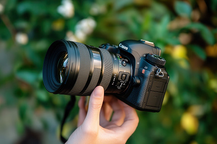 Holding a camera in hand with lens, a Photo by Pavel_design