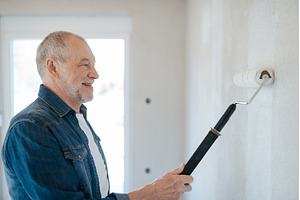 Senior man painting walls with, a Person Photo by HalfPoint