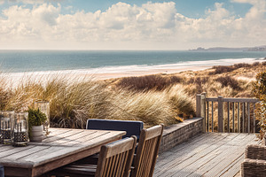 Outdoor dining terrace overlooking a sandy beach and ocean, enjo, a Photo by Studio ANNA
