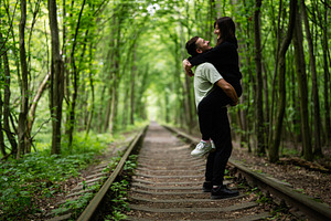 Romantic couple sharing a joyful moment on forest railway tracks, a Photo by AS photostudio