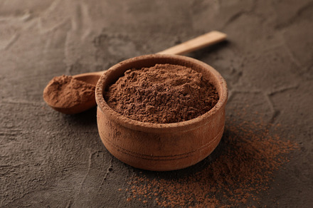 Bowl with cocoa powder and spoon on brown background, closeup, a Food & Drink Photo by AtlasStudio