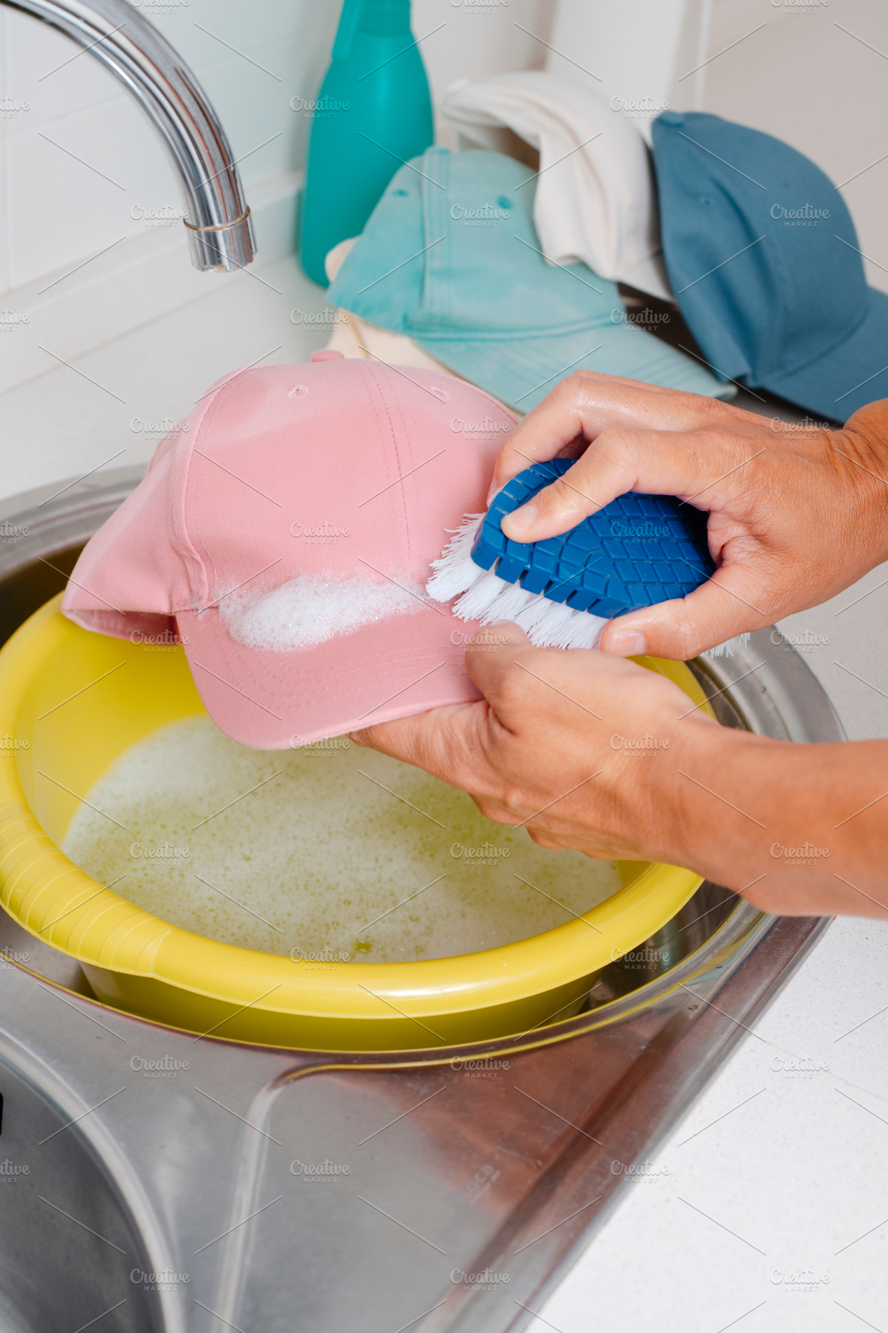 man is washing a pink cap using a brush, a Photo by Nito