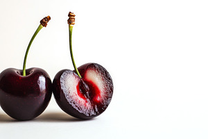 Halved fresh cherries on white, a Photo by Beautiful things