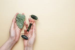 Female hands holding marble face roller and gua sha tools for skincare routine, a Photo by matucha