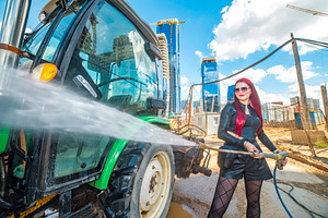 Red haired woman cleaning green tractor with pressure washer wit, a Photo by Pictures for you!!!!!!!!!