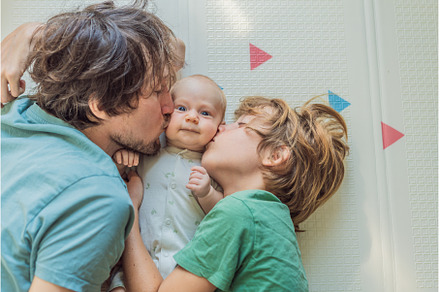 Father, son, and newborn baby lying