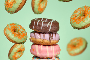A stack of four brightly glazed donuts on a table with green don, a Food & Drink Photo by ndanko