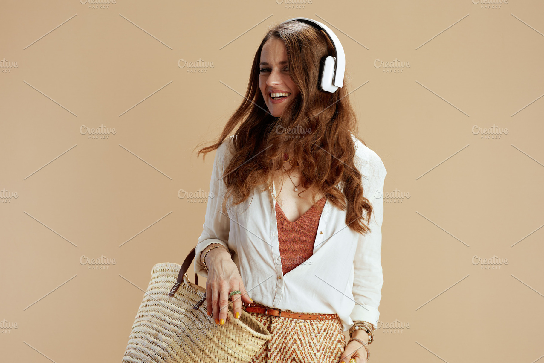 smiling elegant woman listening to music on beige, a Person Photo by Alliance Images