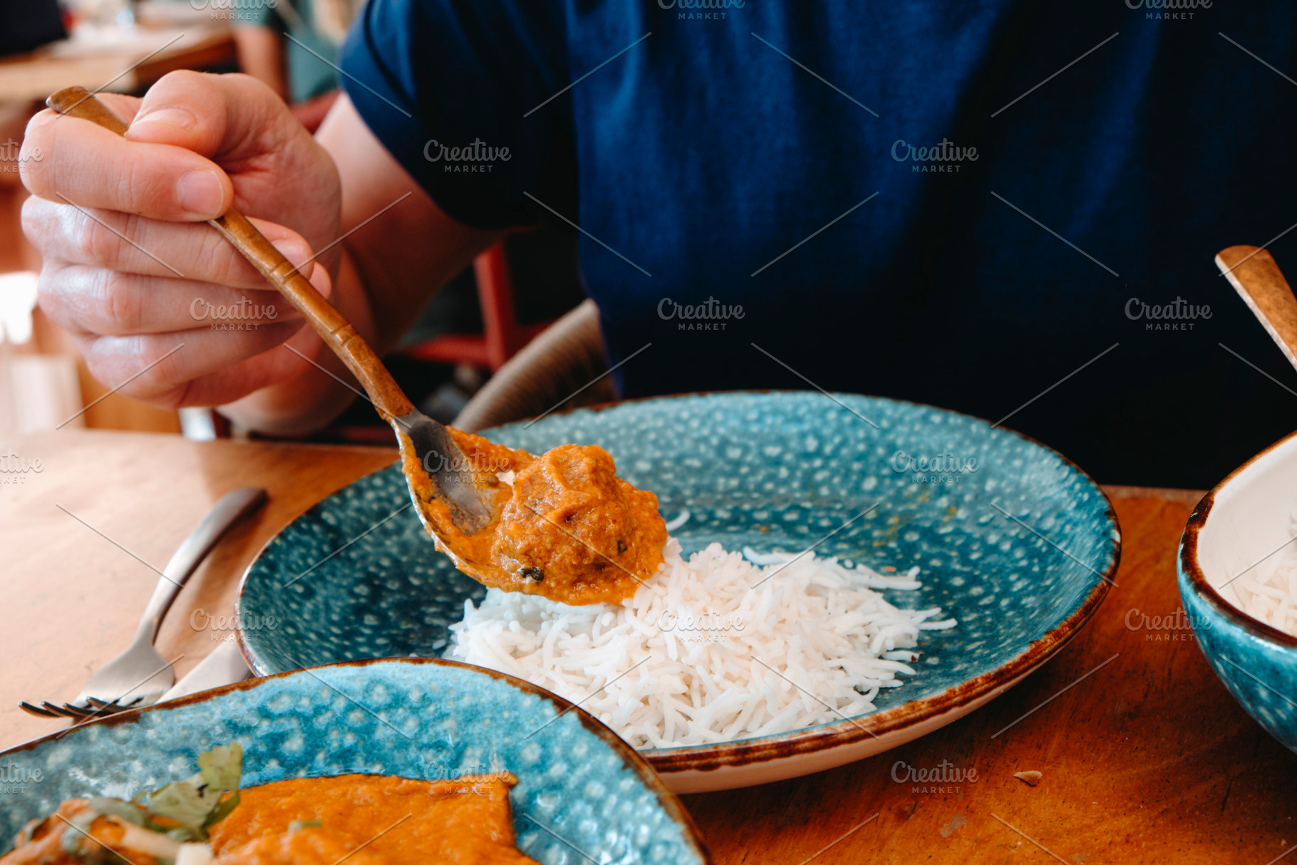 a man adding tikka masala to his rice, a Photo by Nito